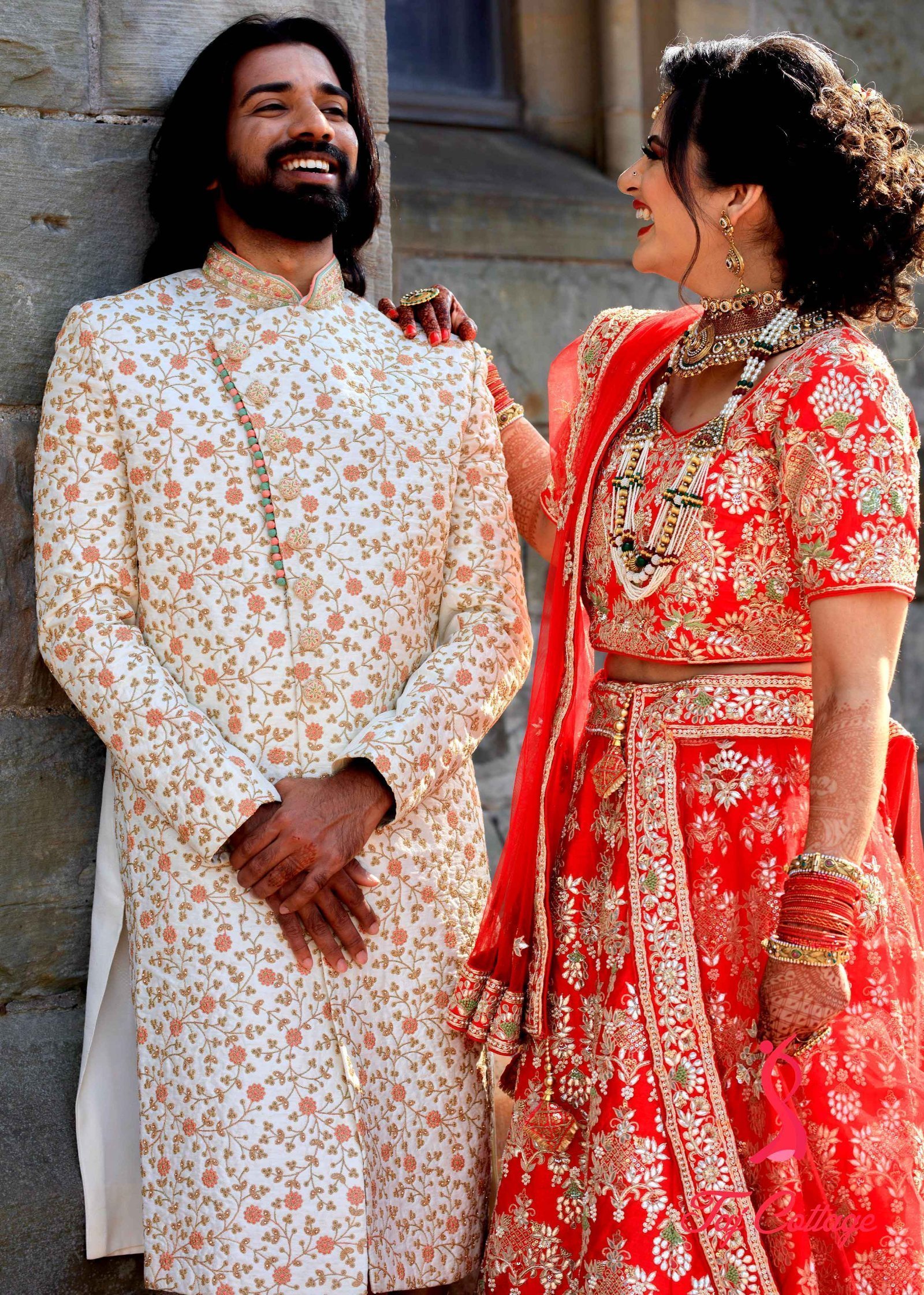 Young Indian Bride groom posing for photograph during their wedding. The  couple is wearing traditional indian wedding dress which is designer red  lehenga for bride and sherwani for groom foto de Stock |